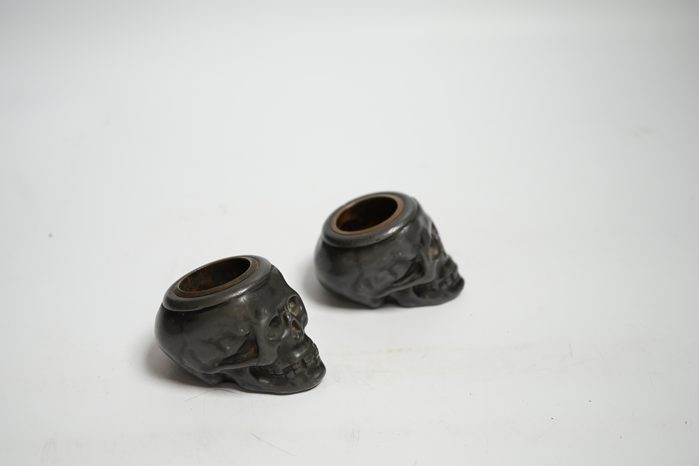 A pair of late 19th century skull shaped pewter match holders, 5cm tall